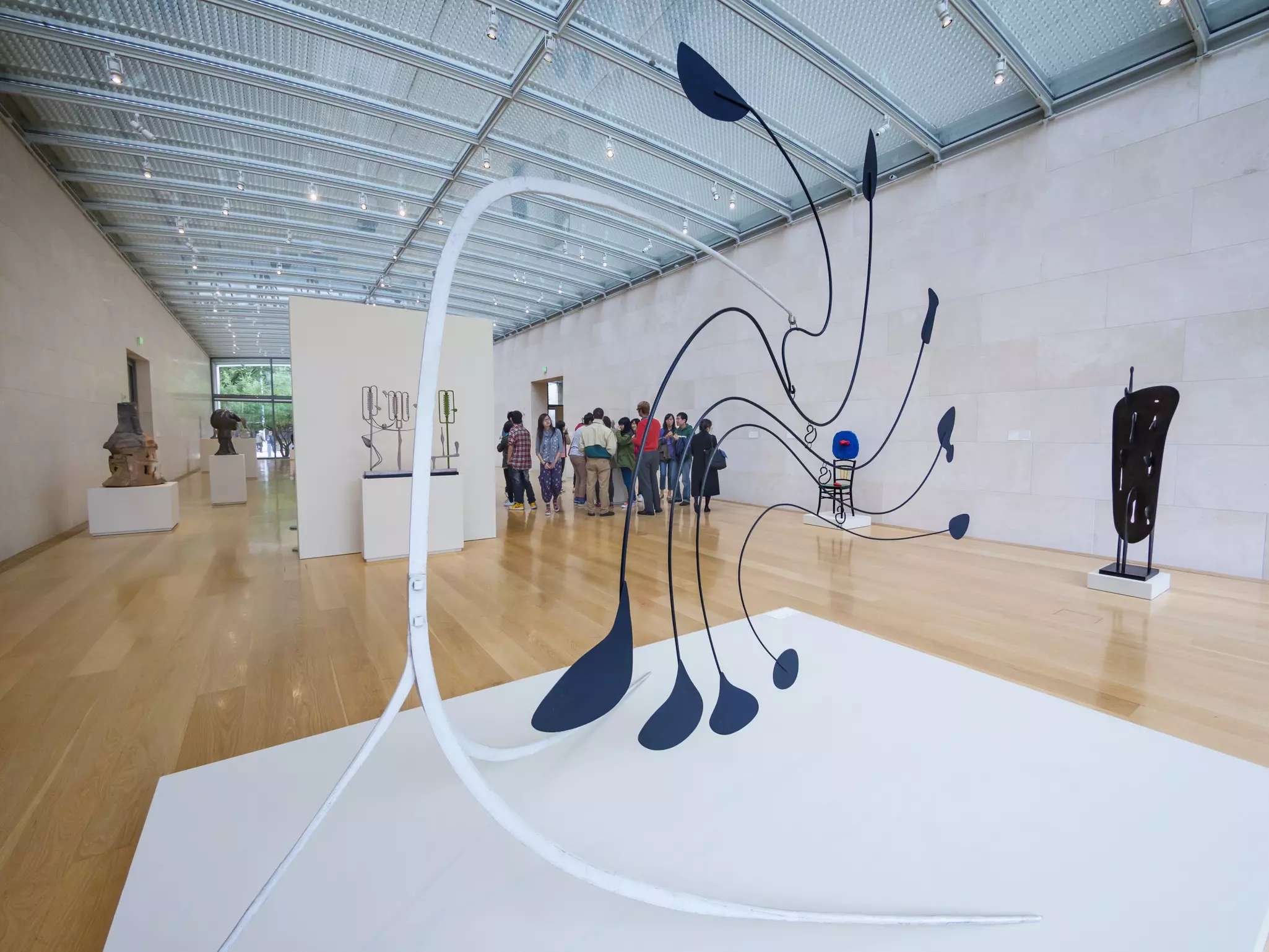 Modern and contemporary art sculptures on display in glass-ceilinged museum.