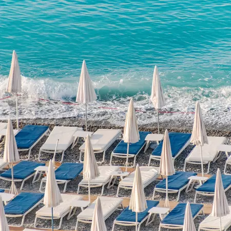 Beach umbrellas and blue loungers Nice, France. 