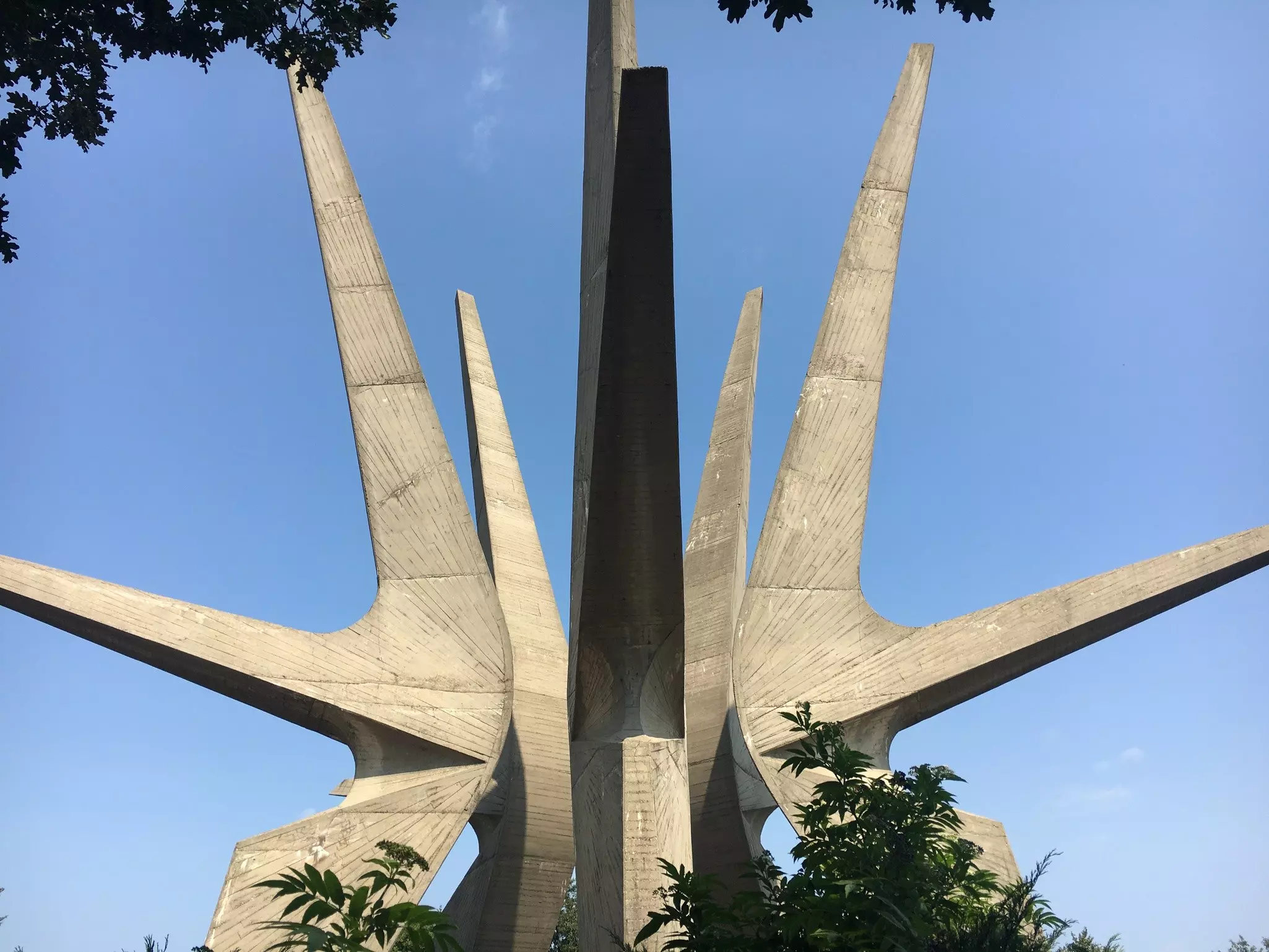 A large concrete structure branches out into a three-dimensional star shape against a blue sky.