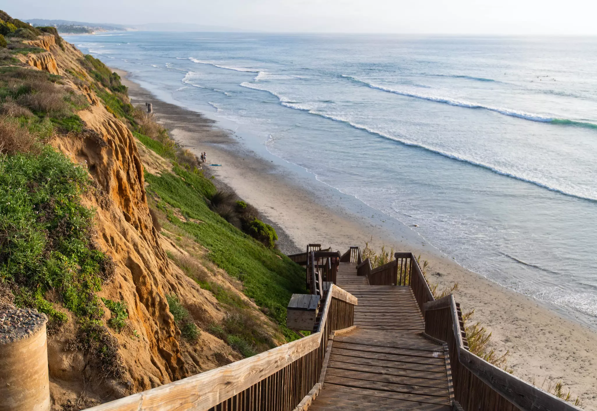 Wooden steps lead down to a beach backed by sandy cliffs.