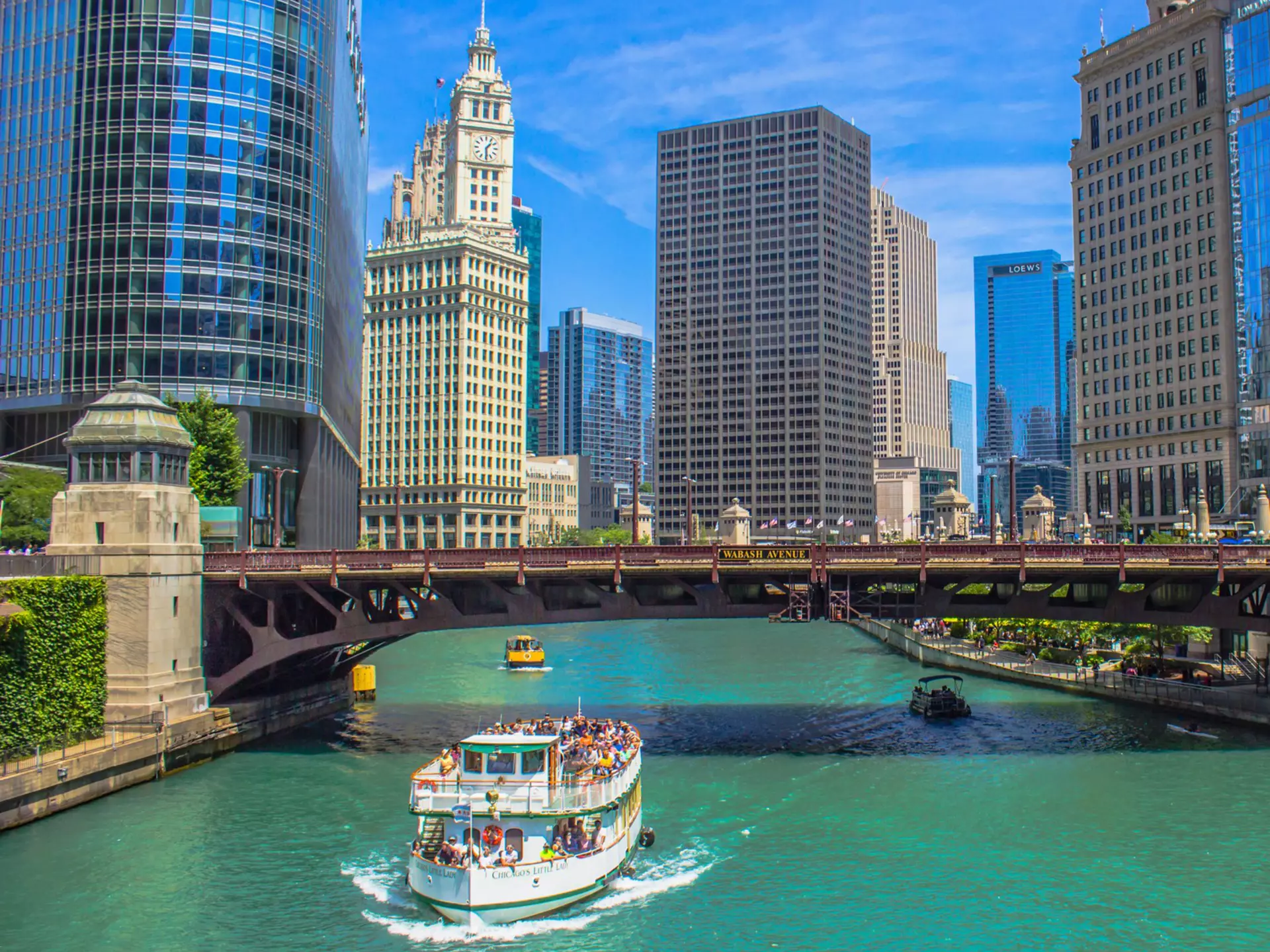 A boat on the Chicago River passes beside landmark Chicago buildings, USA.