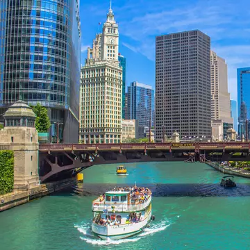 A boat on the Chicago River passes beside landmark Chicago buildings, USA.