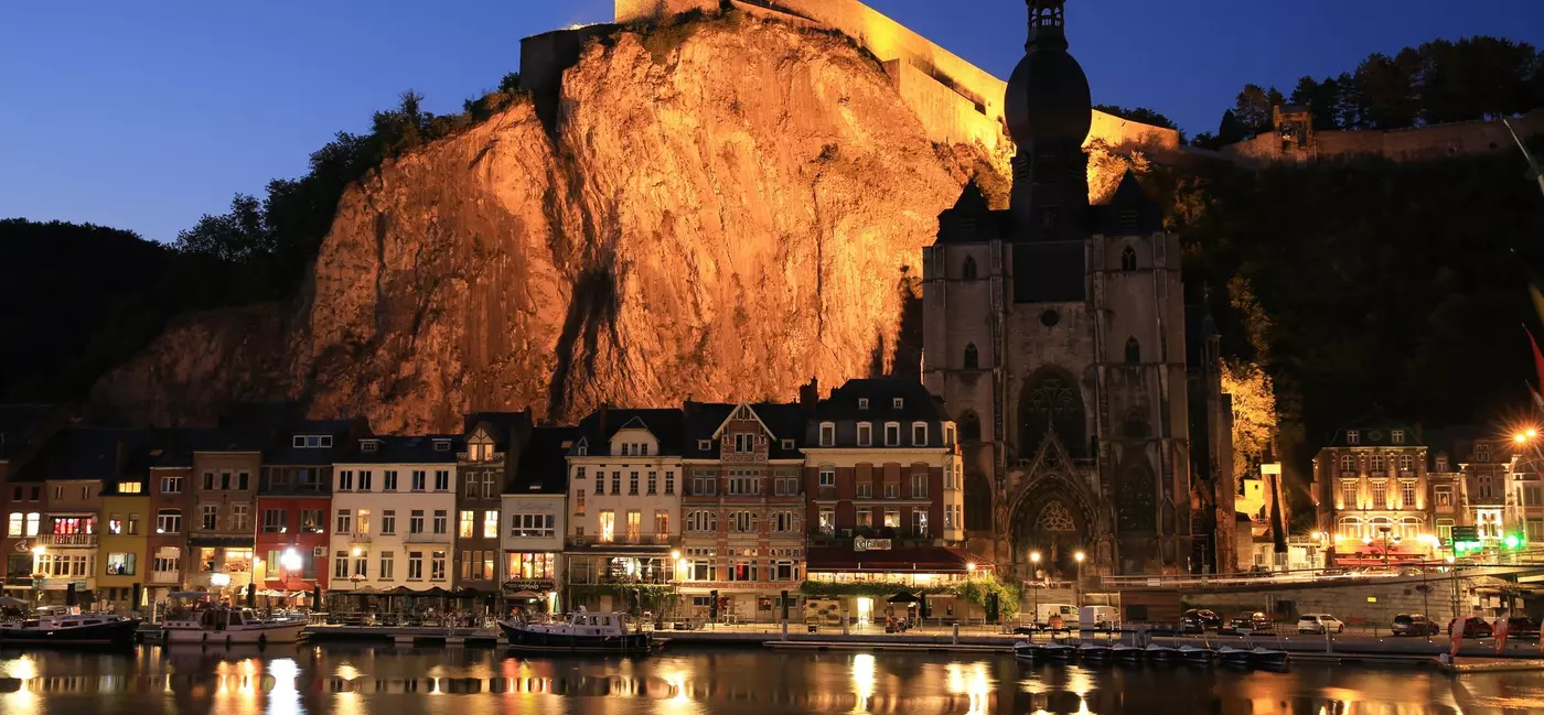 The dramatic limestone cliffs of Dinant illuminated at night.