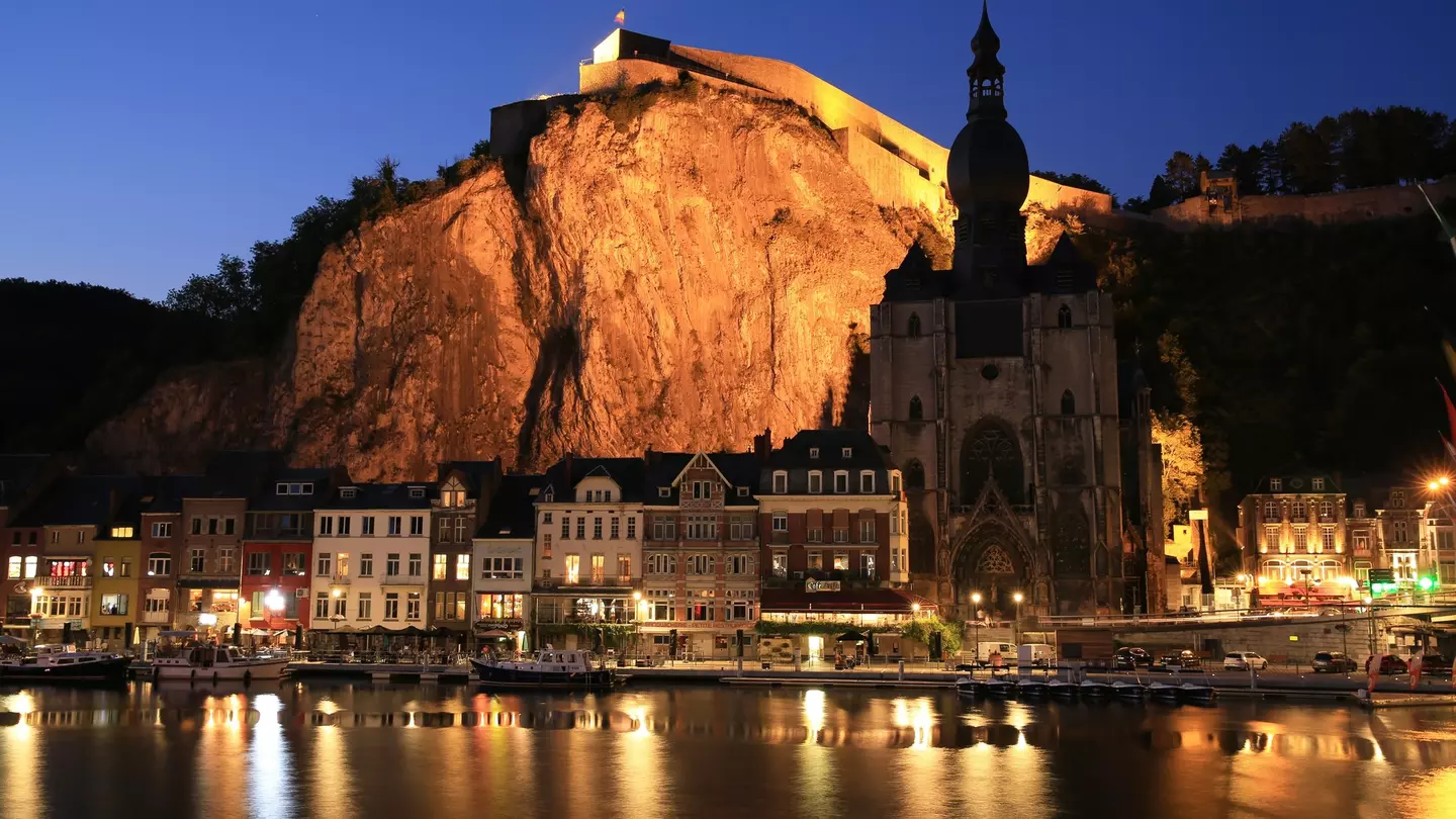 Historic downtown in Dinant, Namur, Wallonia, Belgium lit up at night with light reflecting off the water