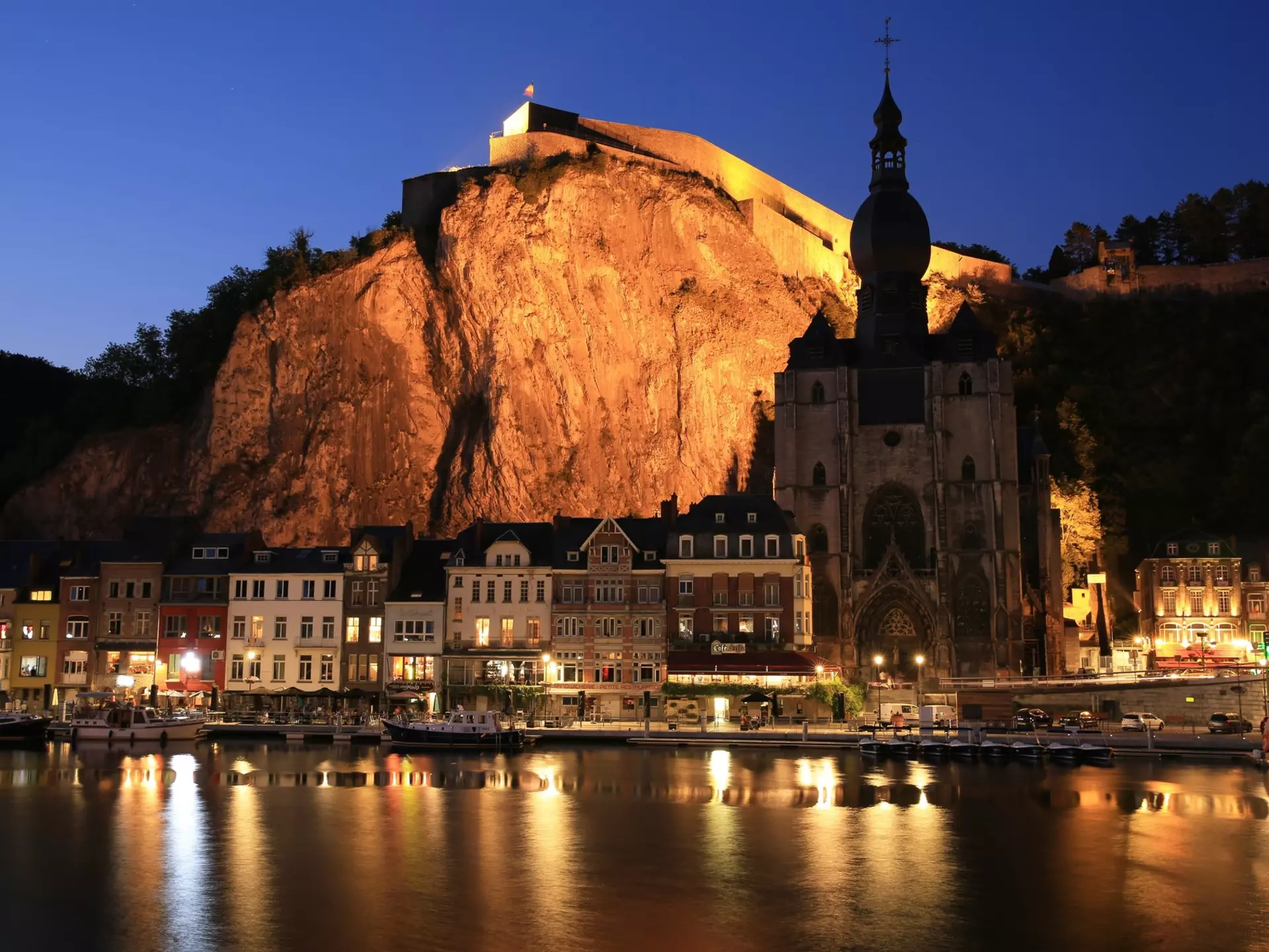 Historic downtown in Dinant, Namur, Wallonia, Belgium lit up at night with light reflecting off the water