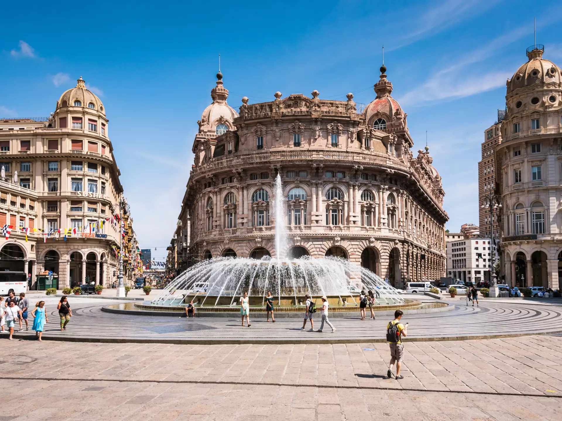 A city square with a large central fountain, lined with grand buildings