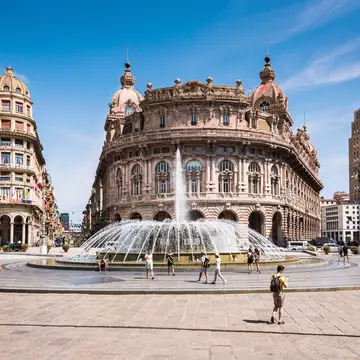 A city square with a large central fountain, lined with grand buildings