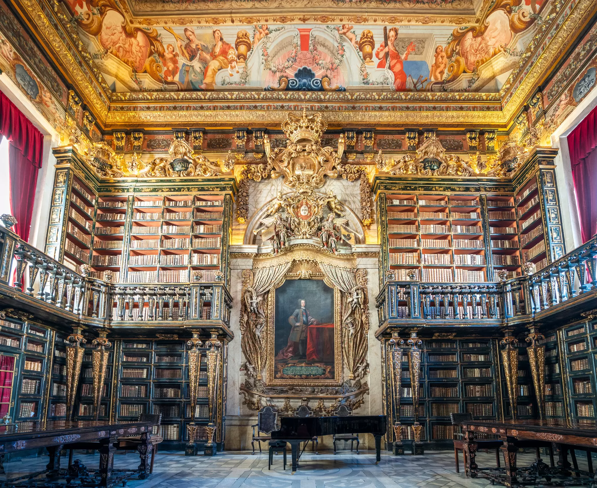 View of bookshelves, paintings and the extravagant decor at Joanina Library in the University of Coimbra in Portugal.
