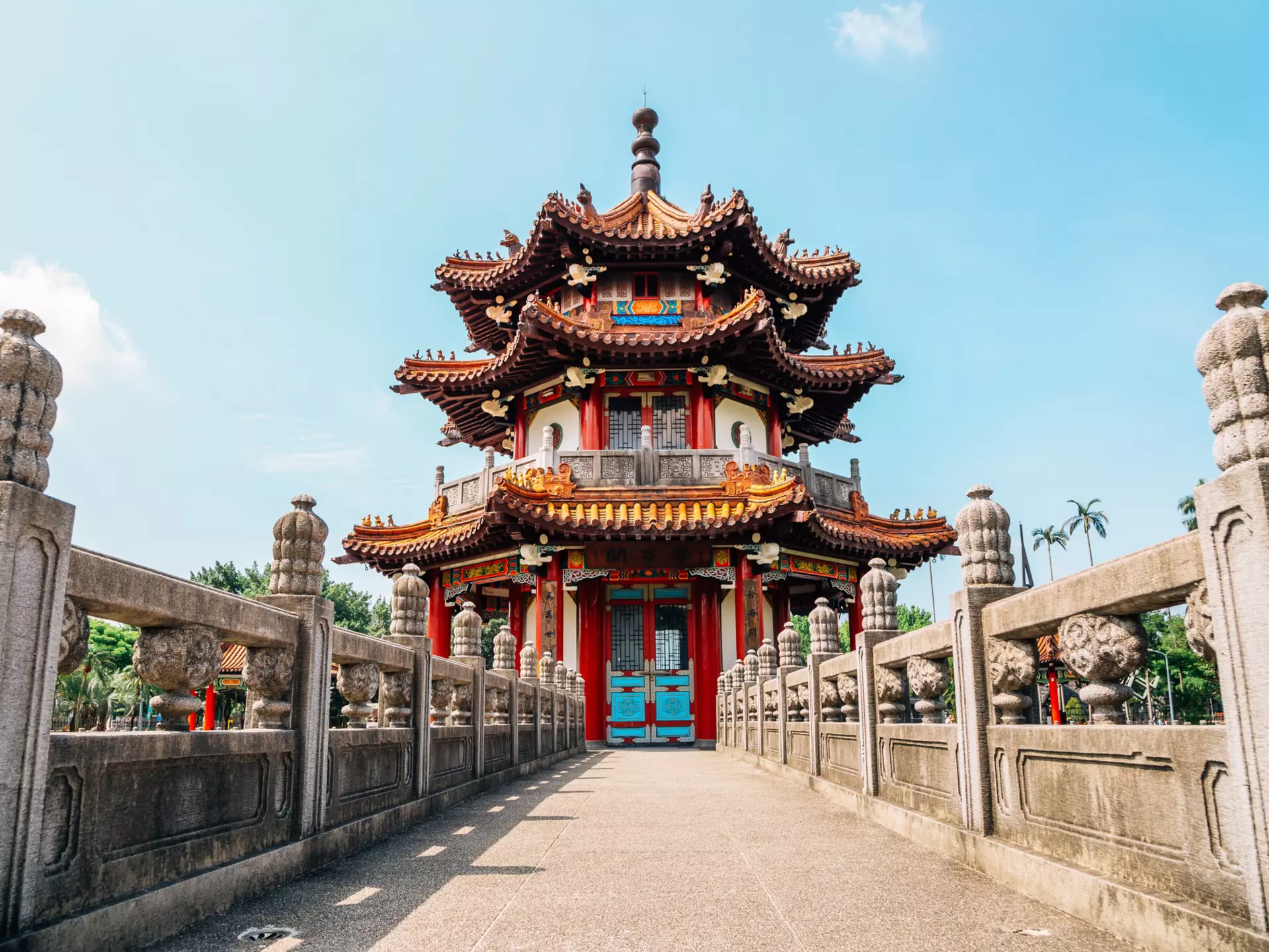 A walkway to a red-roofed pagoda.