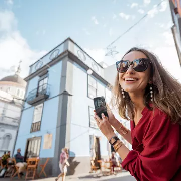 White woman smiling in La Laguna old town city on Tenerife, Spain with a blurry historic building in the background