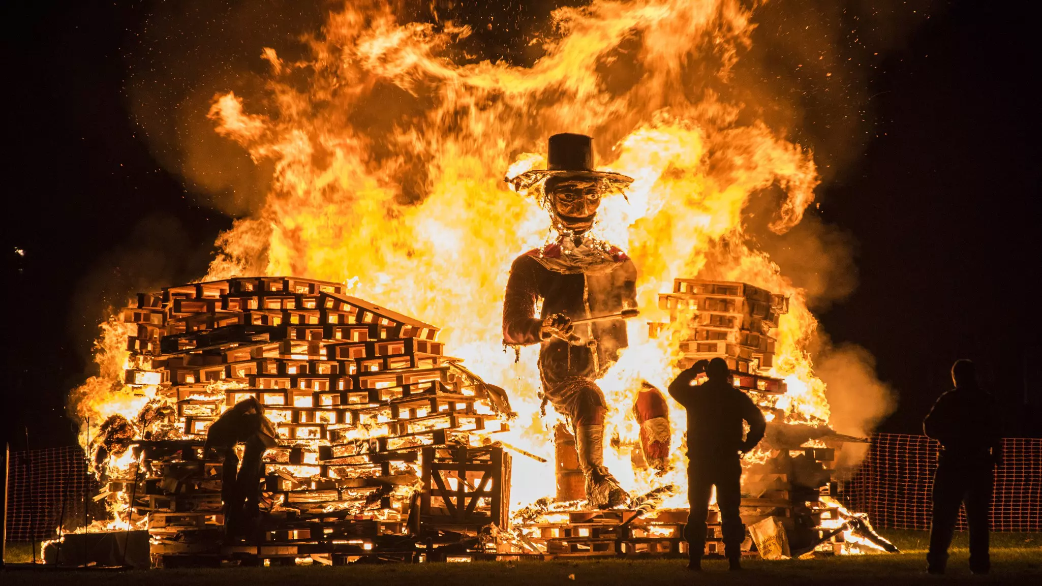 Man standing in front of a Guy Fawkes bonfire during the 5th of November at Lindifield bonfire night, West Sussex, England