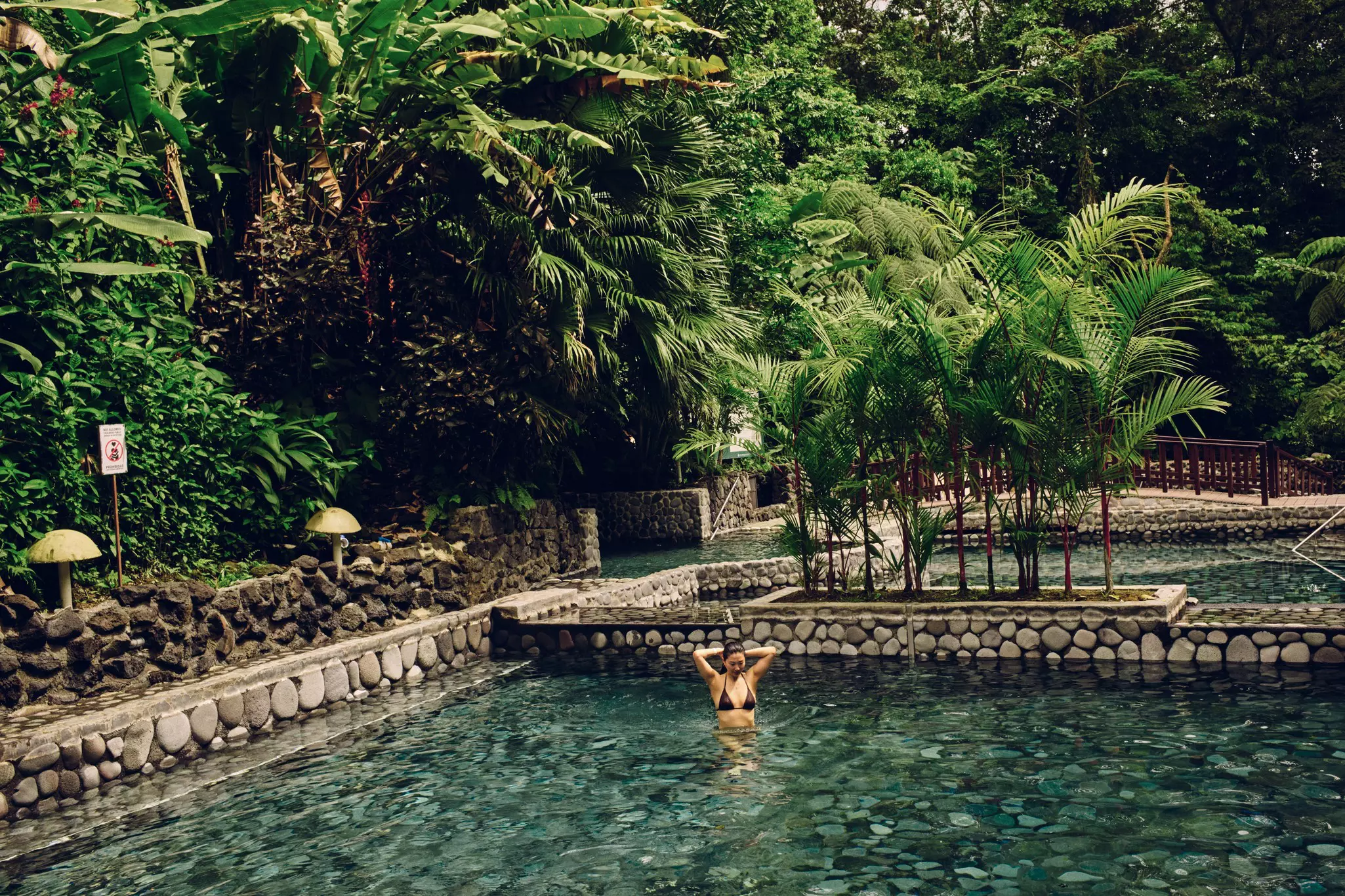 A woman stands in a rock-lined hot spring near Arenal Volcano in La Fortuna, Costa Rica. 