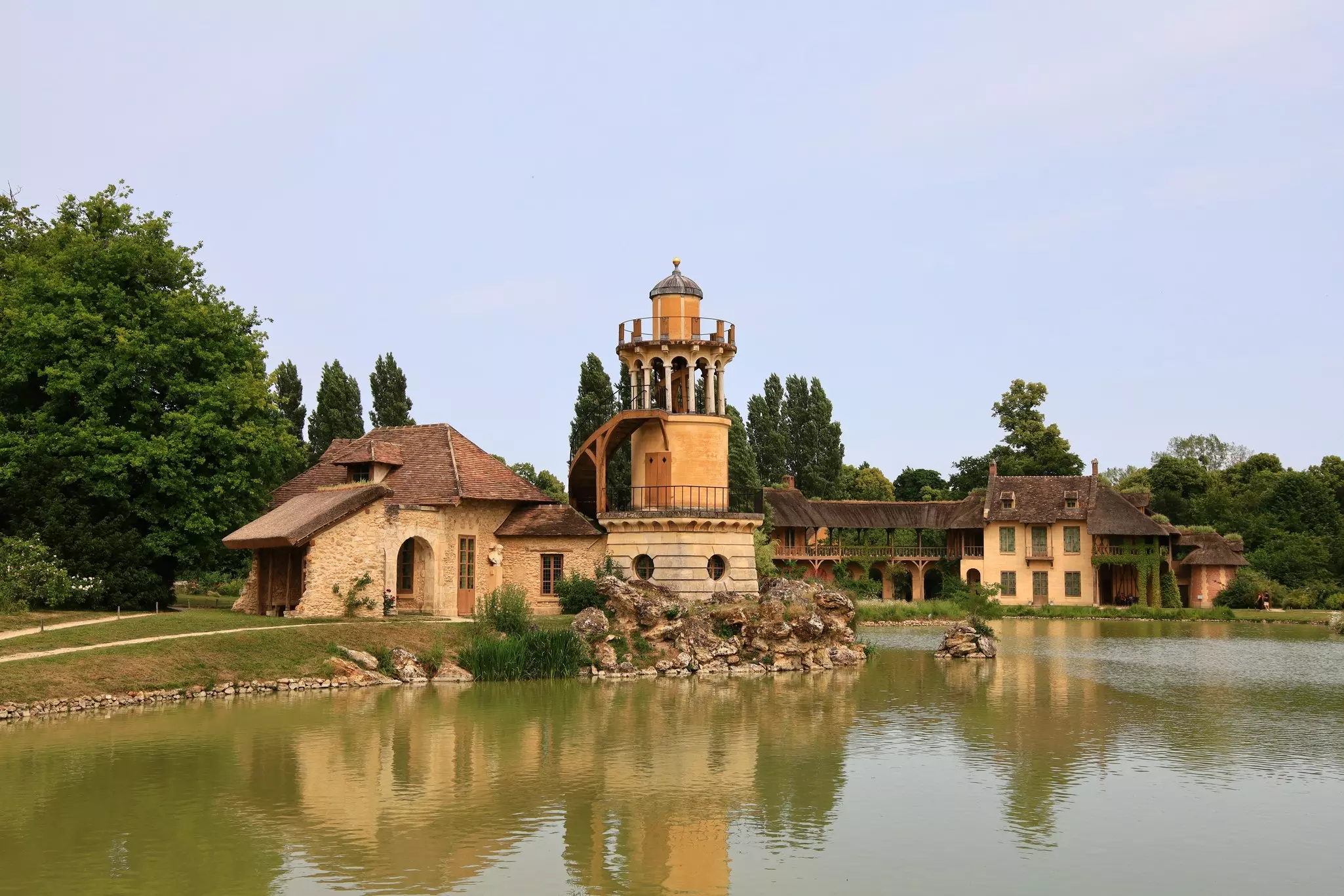 A stone house with a tower by a pond.