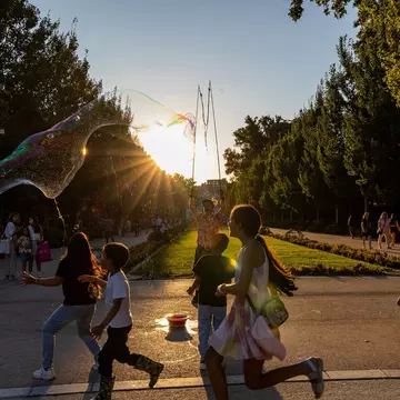 Children at sunset chase the soap bubbles of a street artist in a park in Madrid