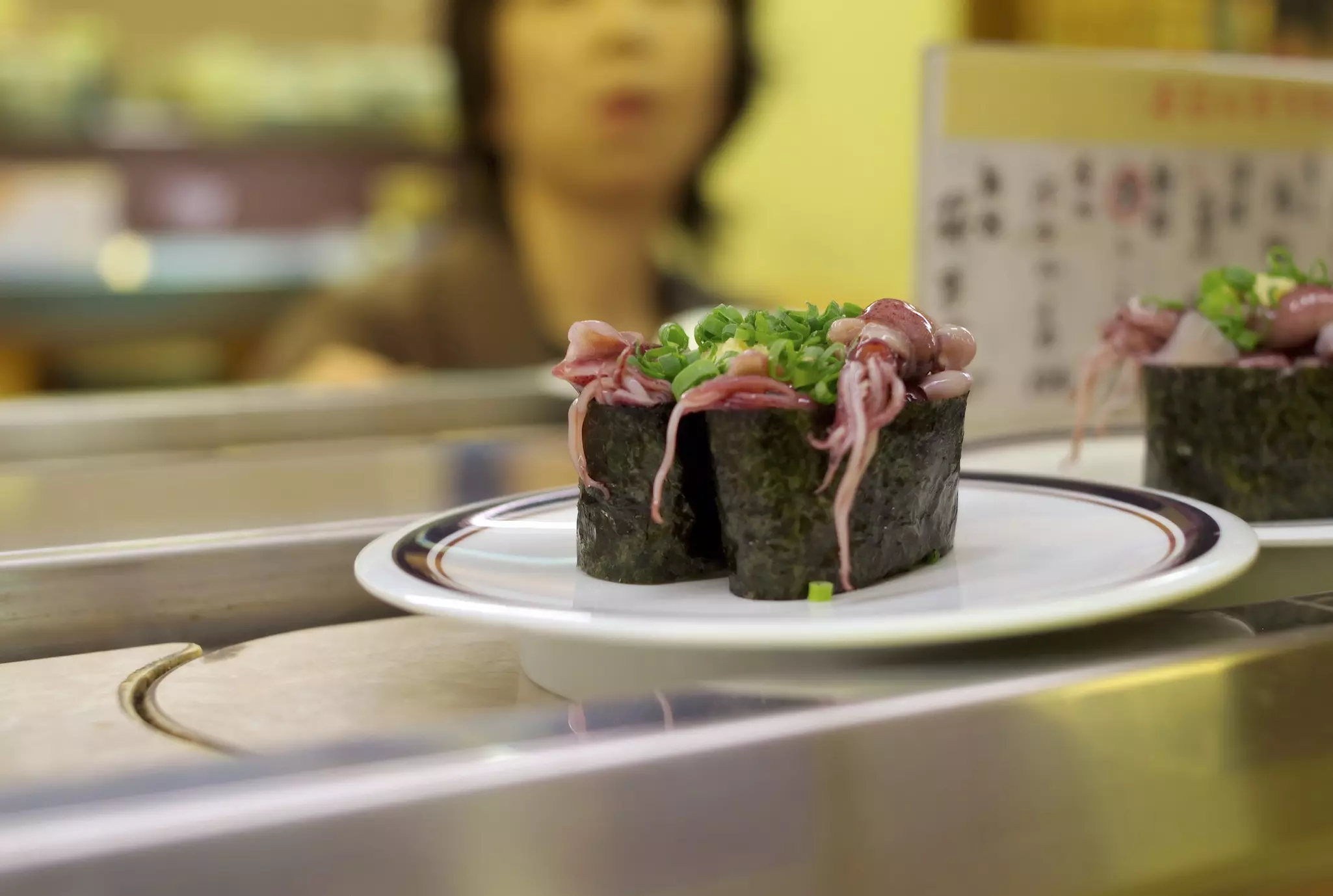 Octopus tentacles spill over the edge of a seaweed wrap on a dish