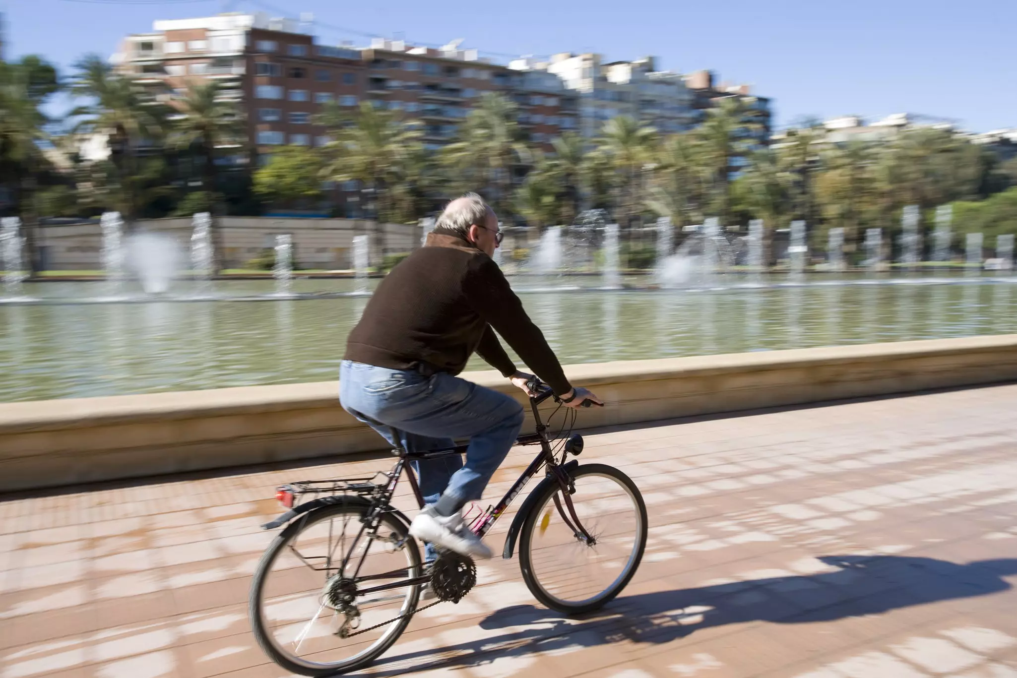 A man riding his bike in Jardines del Turia against a blurry background