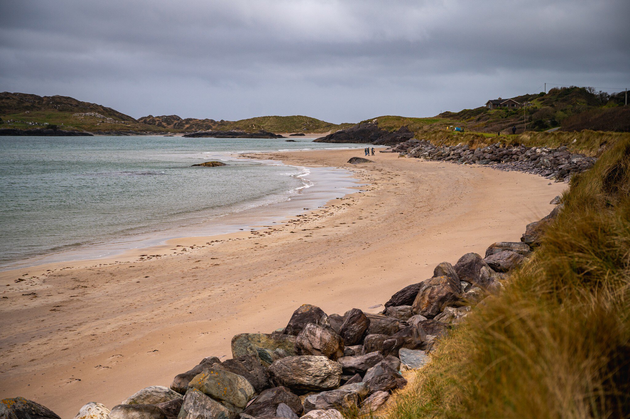 Derrynane Beach, Kerry, Ireland.  Winding rocks, sand, and water, with figures in the distance.