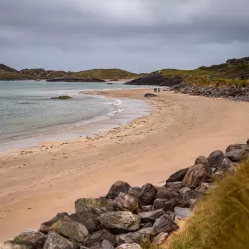 Derrynane Beach, Kerry, Ireland.  Winding rocks, sand, and water, with figures in the distance.