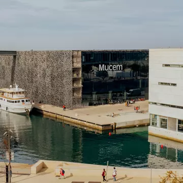 A boat is docked near a portside museum building.
