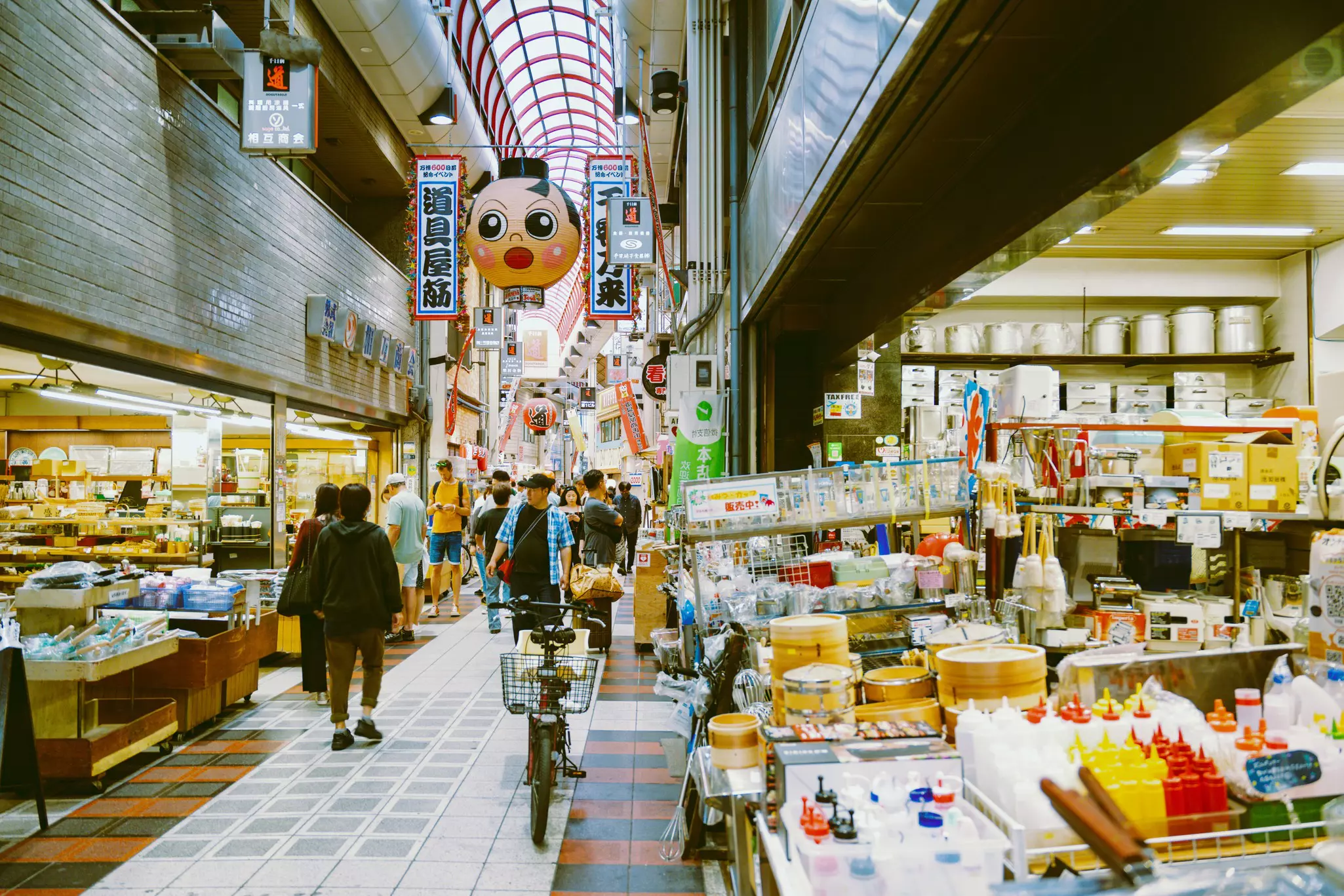 People walking through a shopping area with cooking items in the foreground
