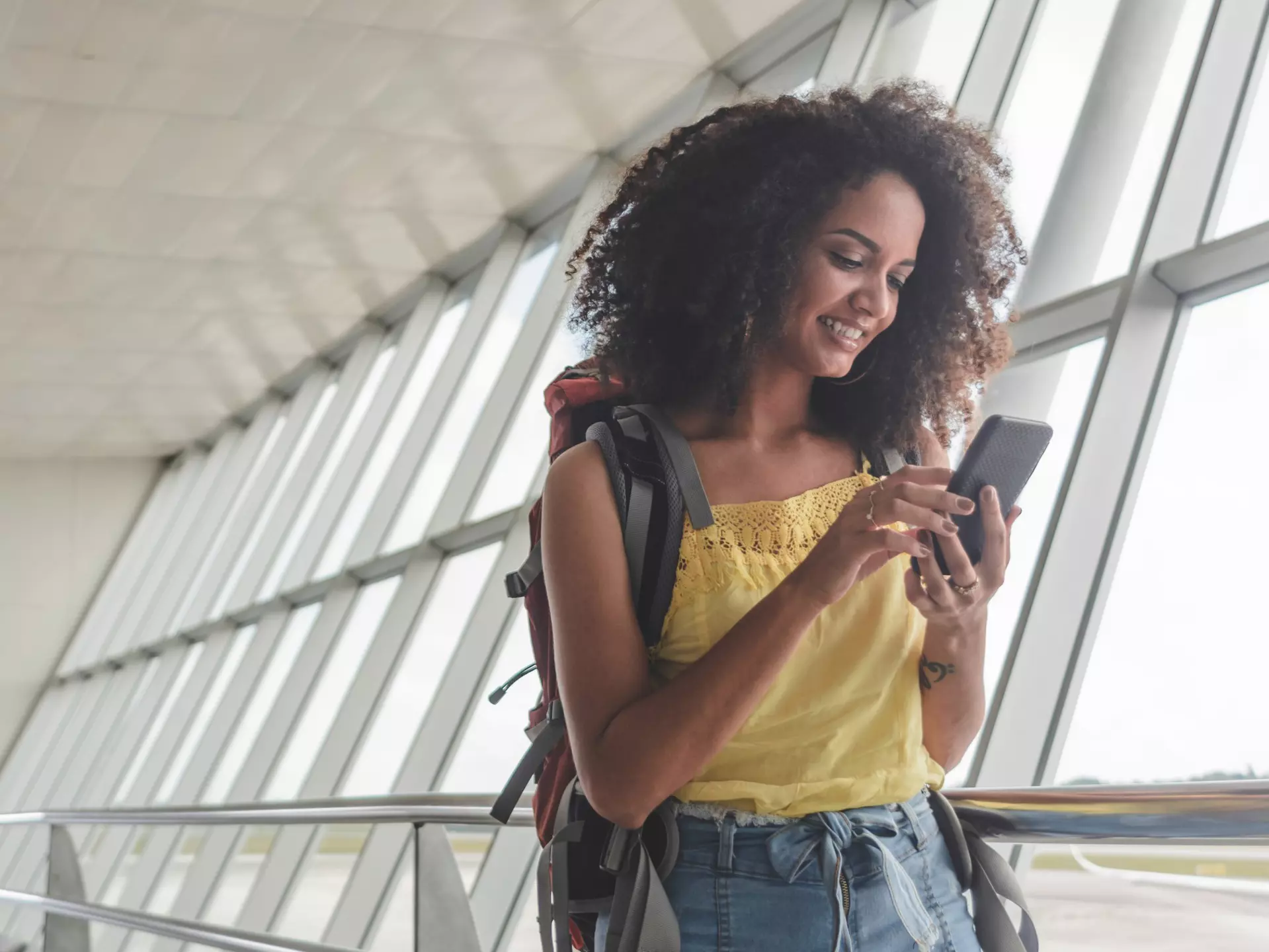 Young woman with backpack checking her boarding schedule at an airport.
1182533901