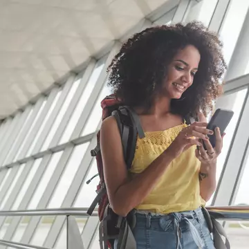 Young woman with backpack checking her boarding schedule at an airport.
1182533901