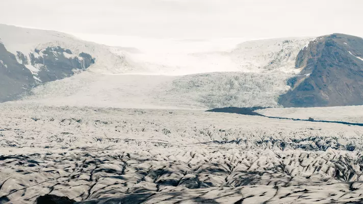 A snow-covered glacier and cracked frozen earth.
