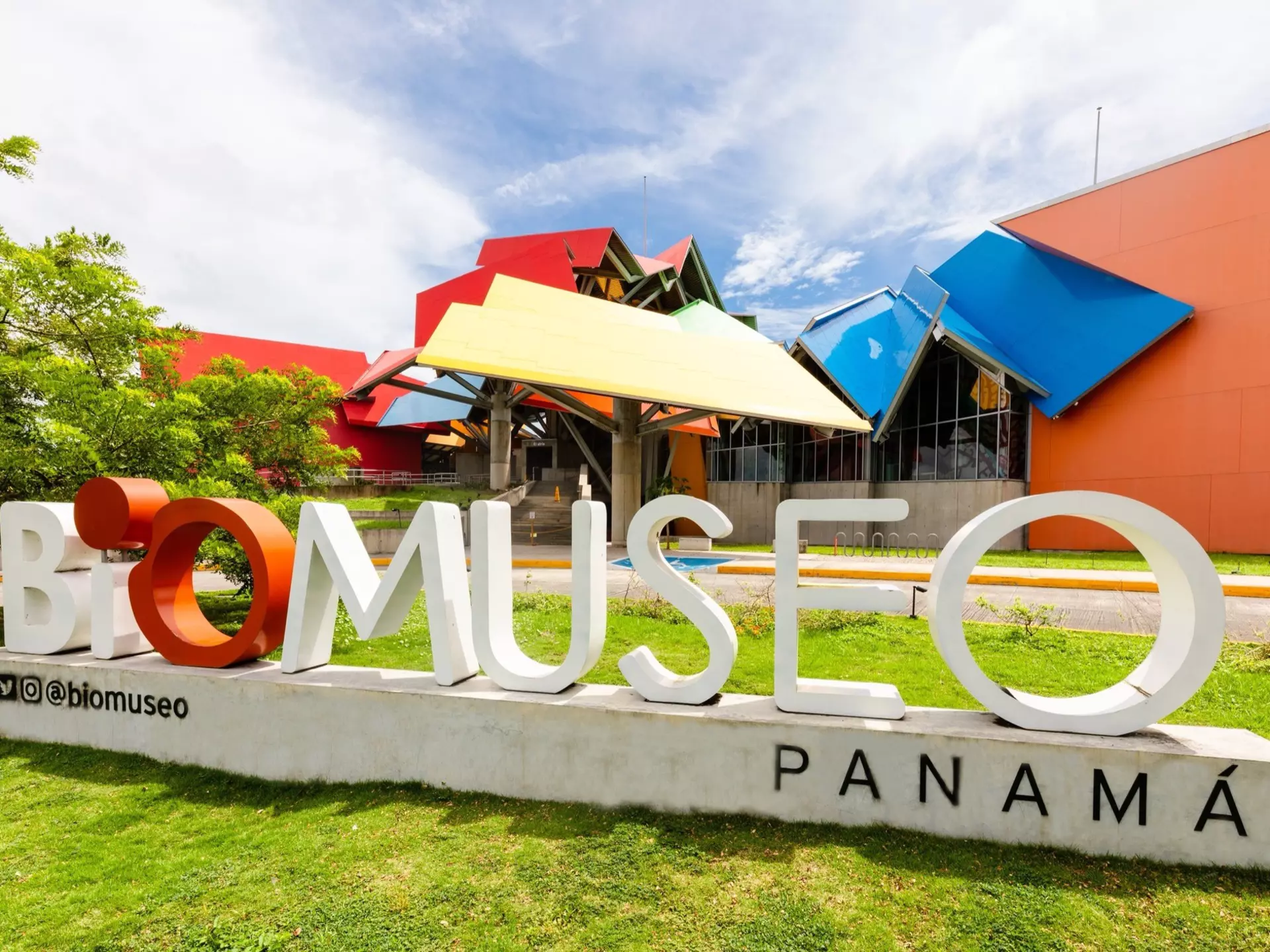 Exterior shot of the colorful BioMuseo in Panama. There is a BioMuseo sign on the grass