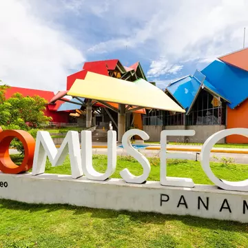 Exterior shot of the colorful BioMuseo in Panama. There is a BioMuseo sign on the grass
