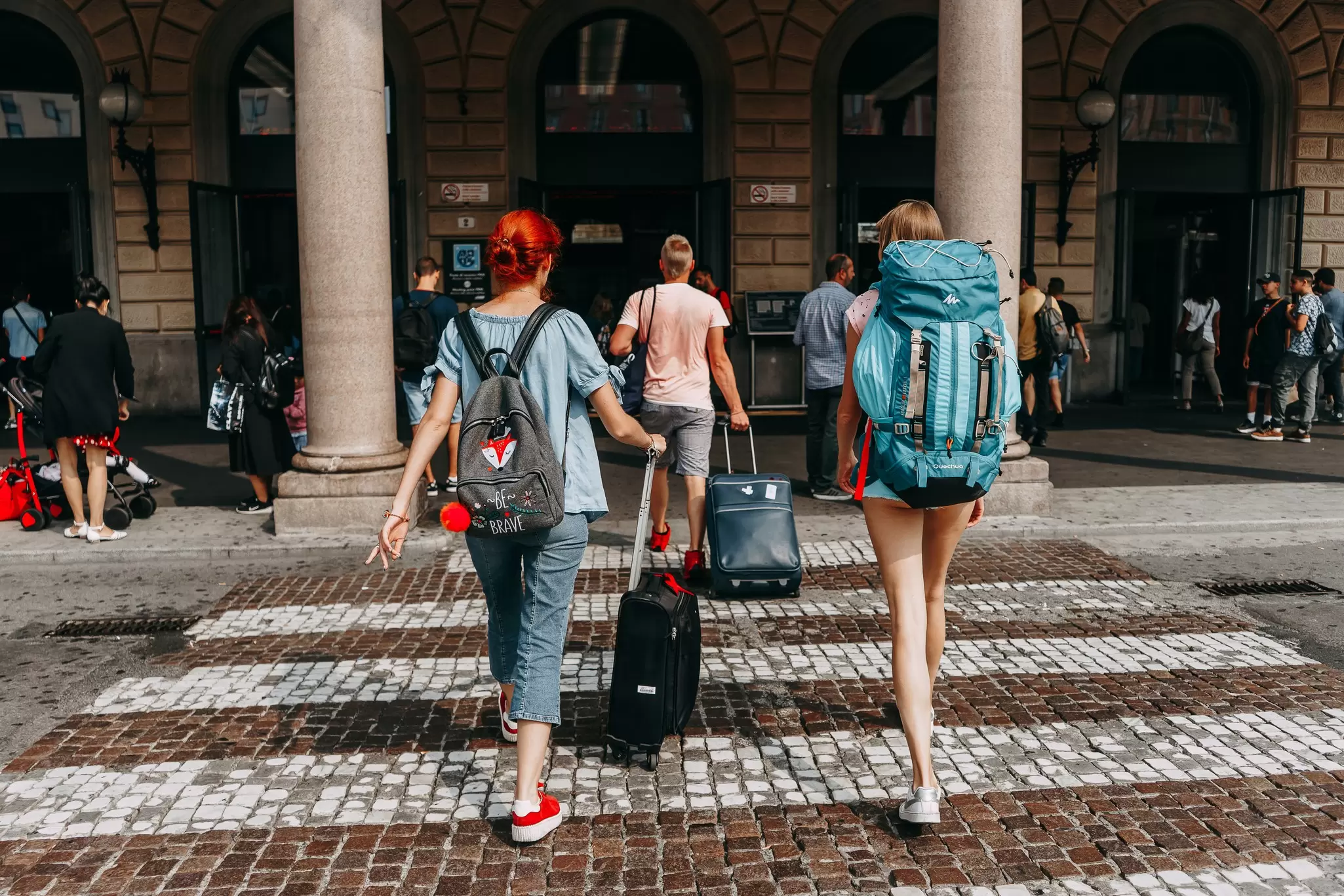 Backpackers cross a cobbled street in Bologna, Italy. 