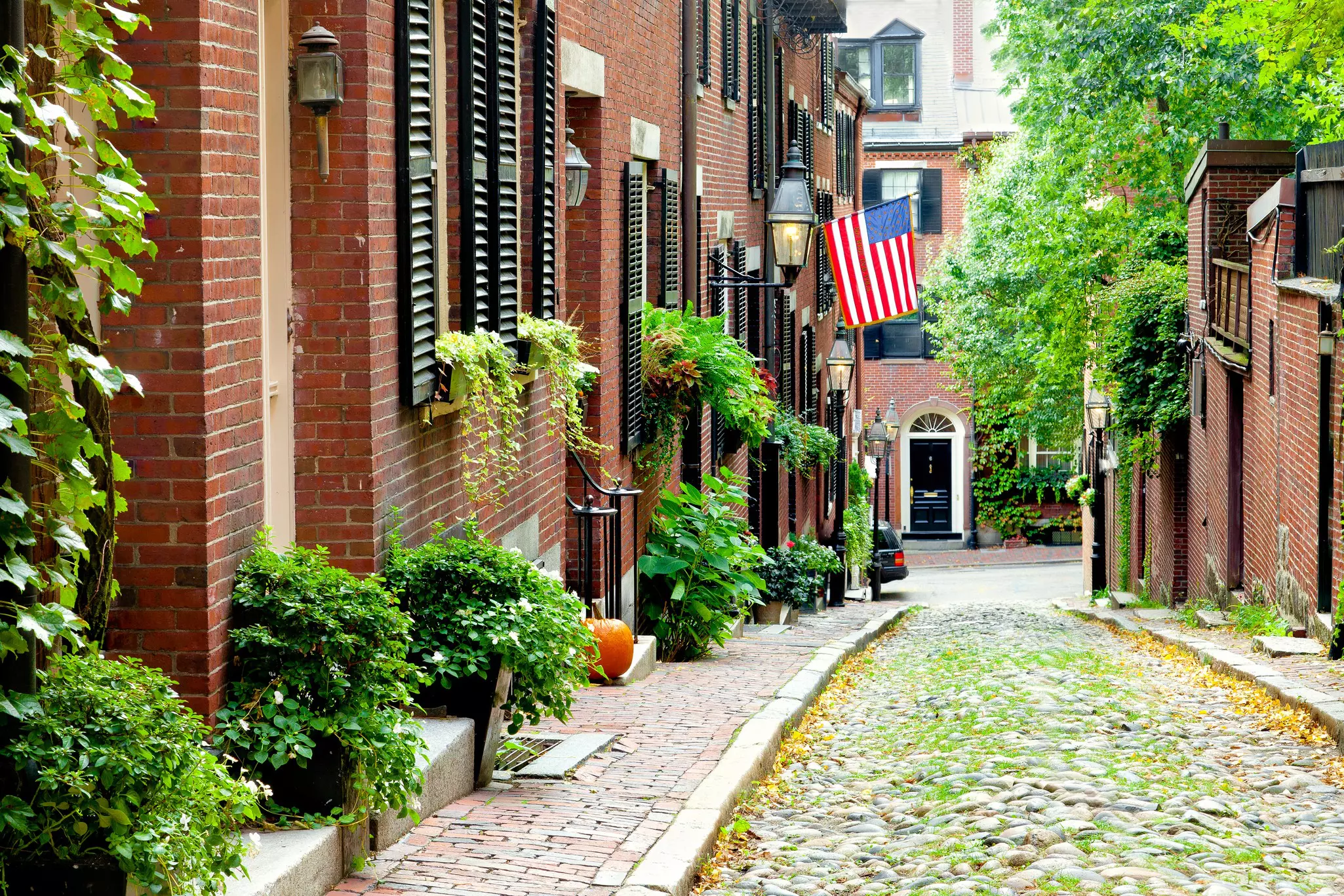 Cobblestone street in Boston.  Historic Acorn Street in Beacon Hill, called the most picturesque street in America, with a row of vintage red brick buildings.