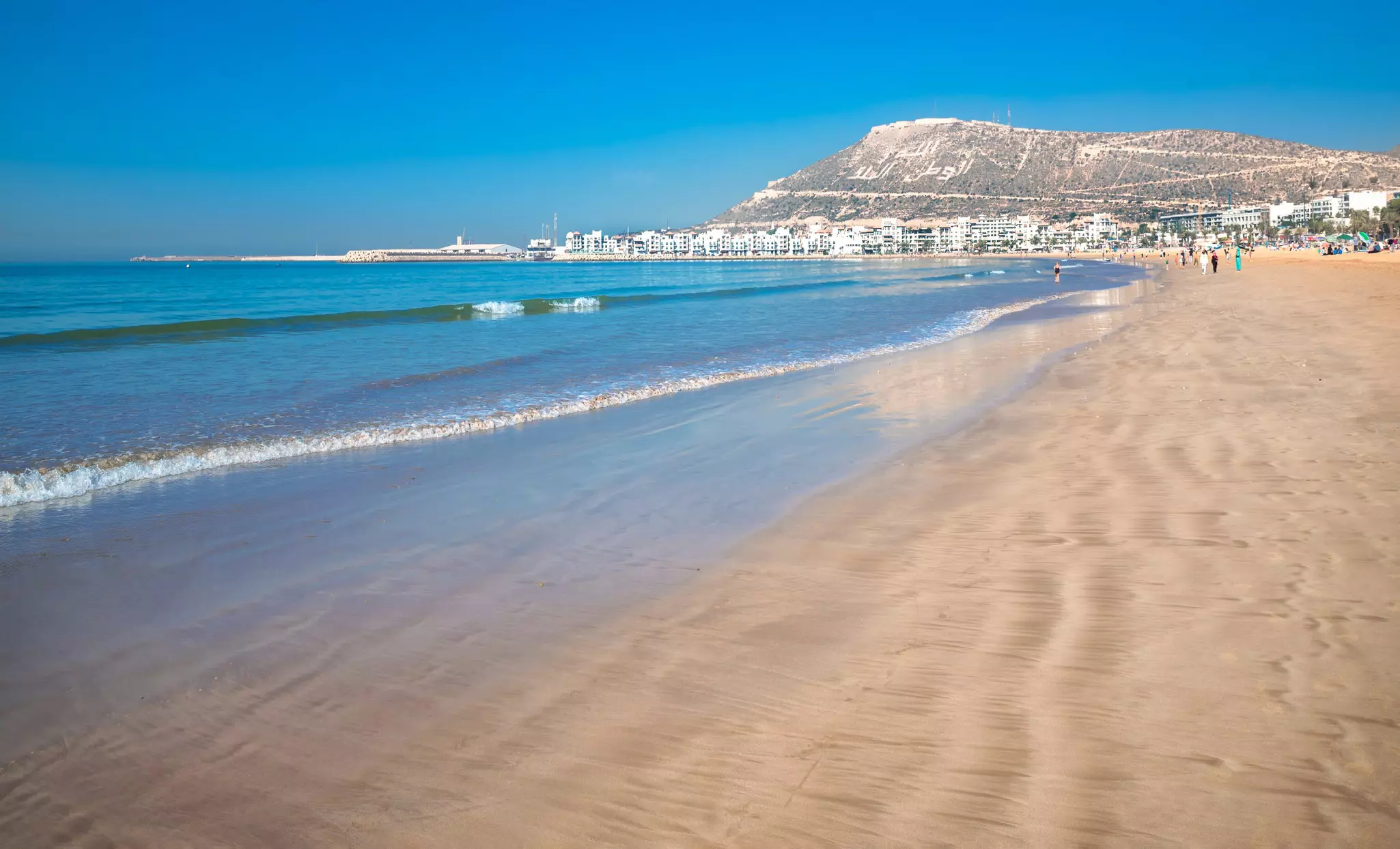 A beach on the Atlantic coast of Morocco in the summertime, with golden sand and turquoise water.