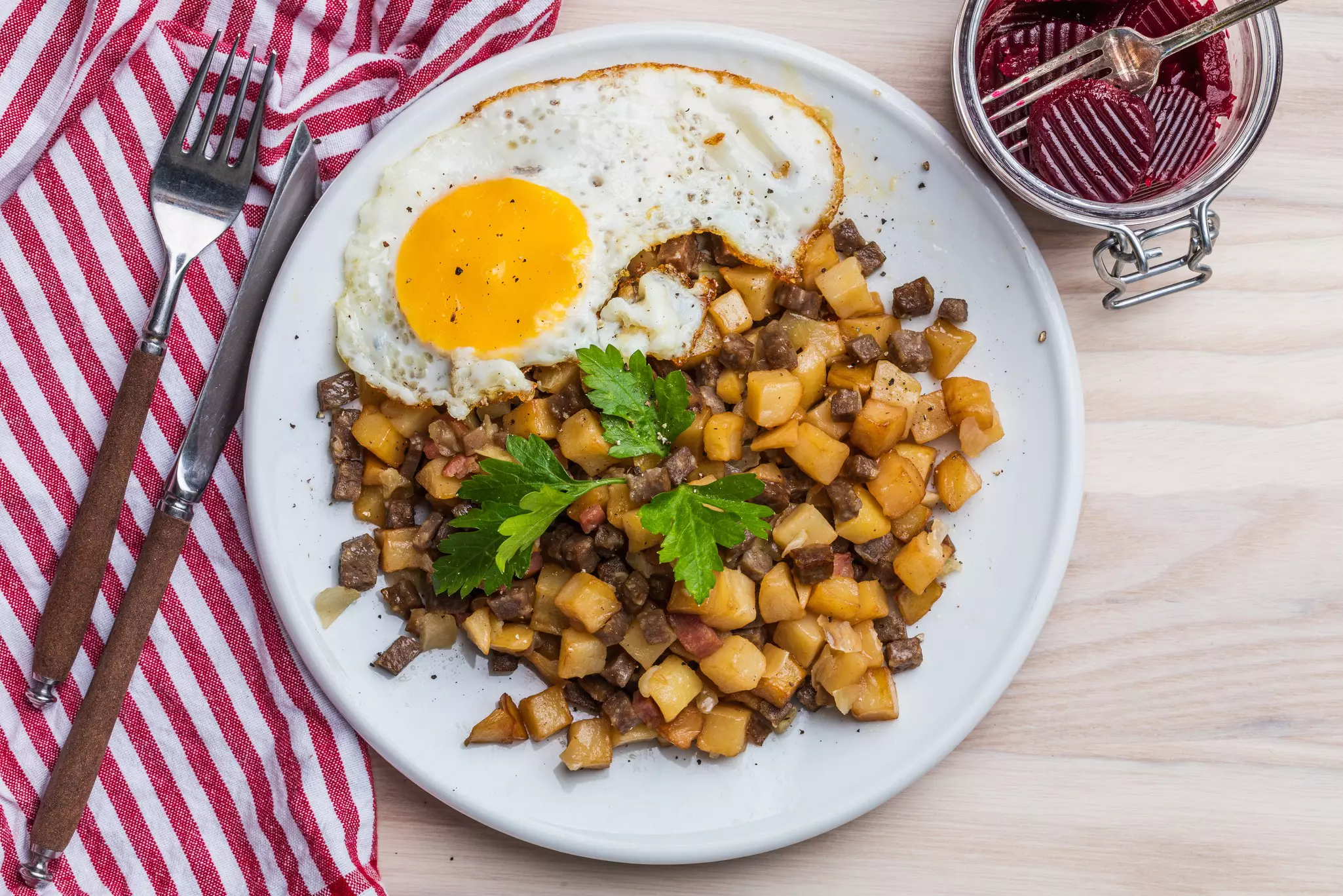 An overhead shot of a plate with a fried egg, potatoes, meat and more.