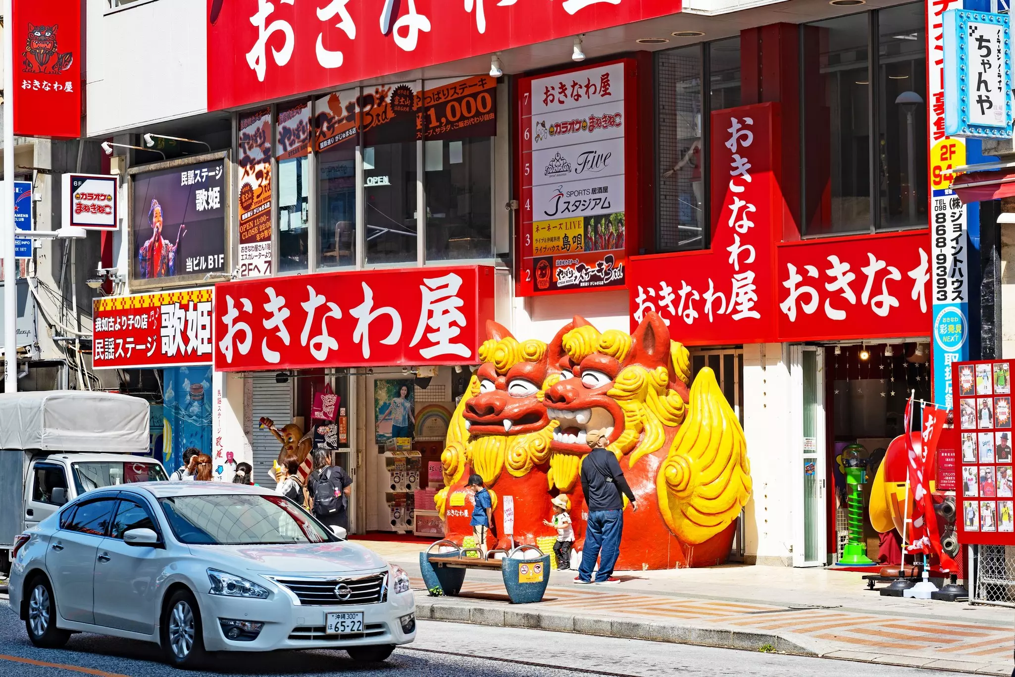 A car goes by a building with a bright red facade with white lettering