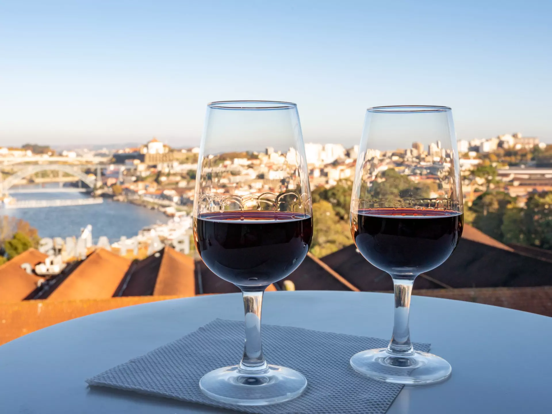 Two glasses of fortified wine on a table with a view over a riverside city.