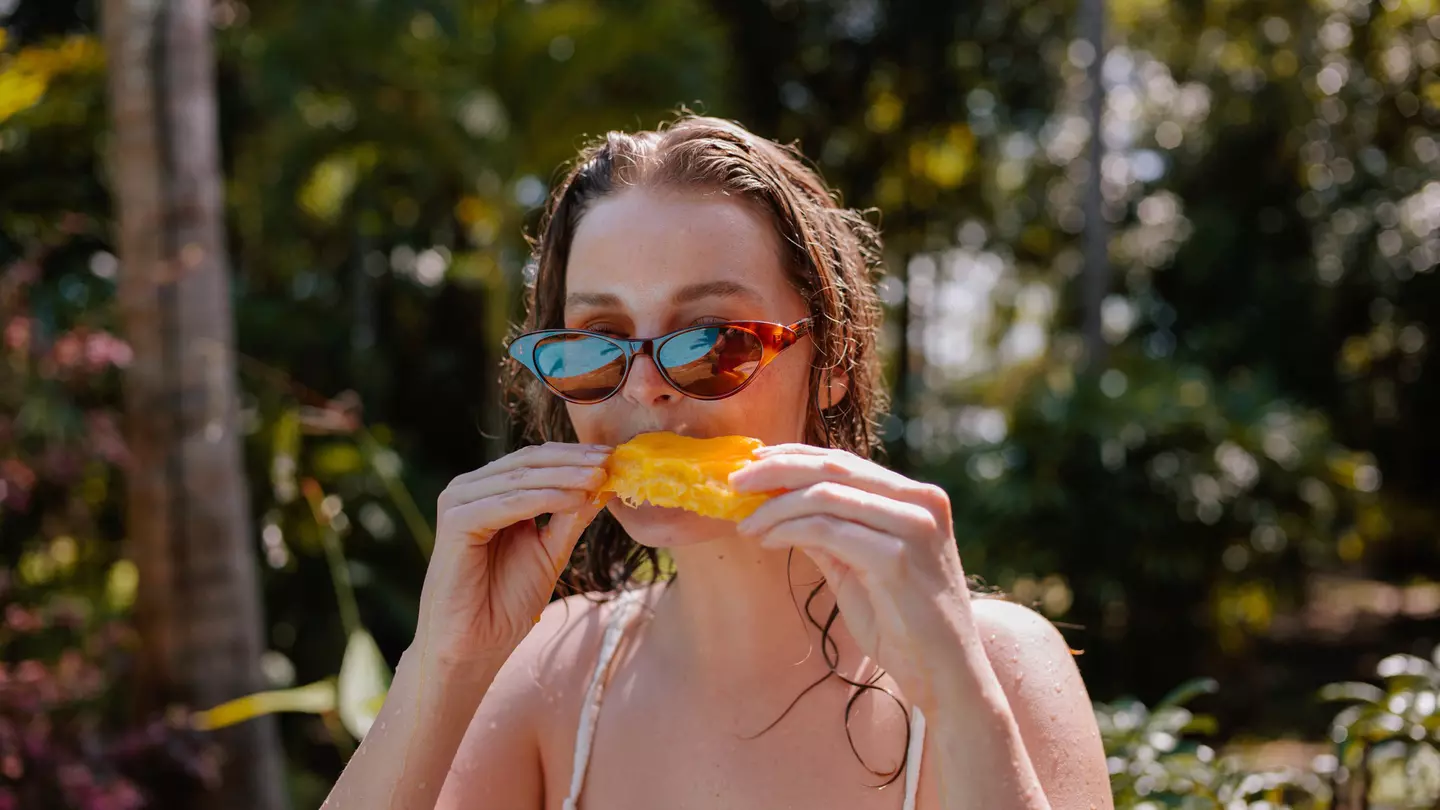 Young Woman Eating Mango On Vacation