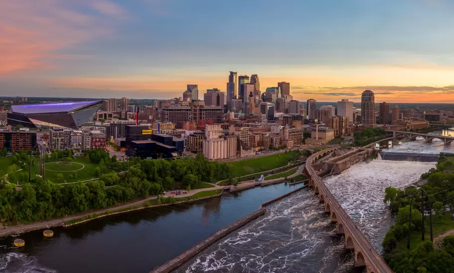 Downtown Minneapolis skyline at sunset with the Stone Arch Bridge over the Mississippi at St Anthony Falls