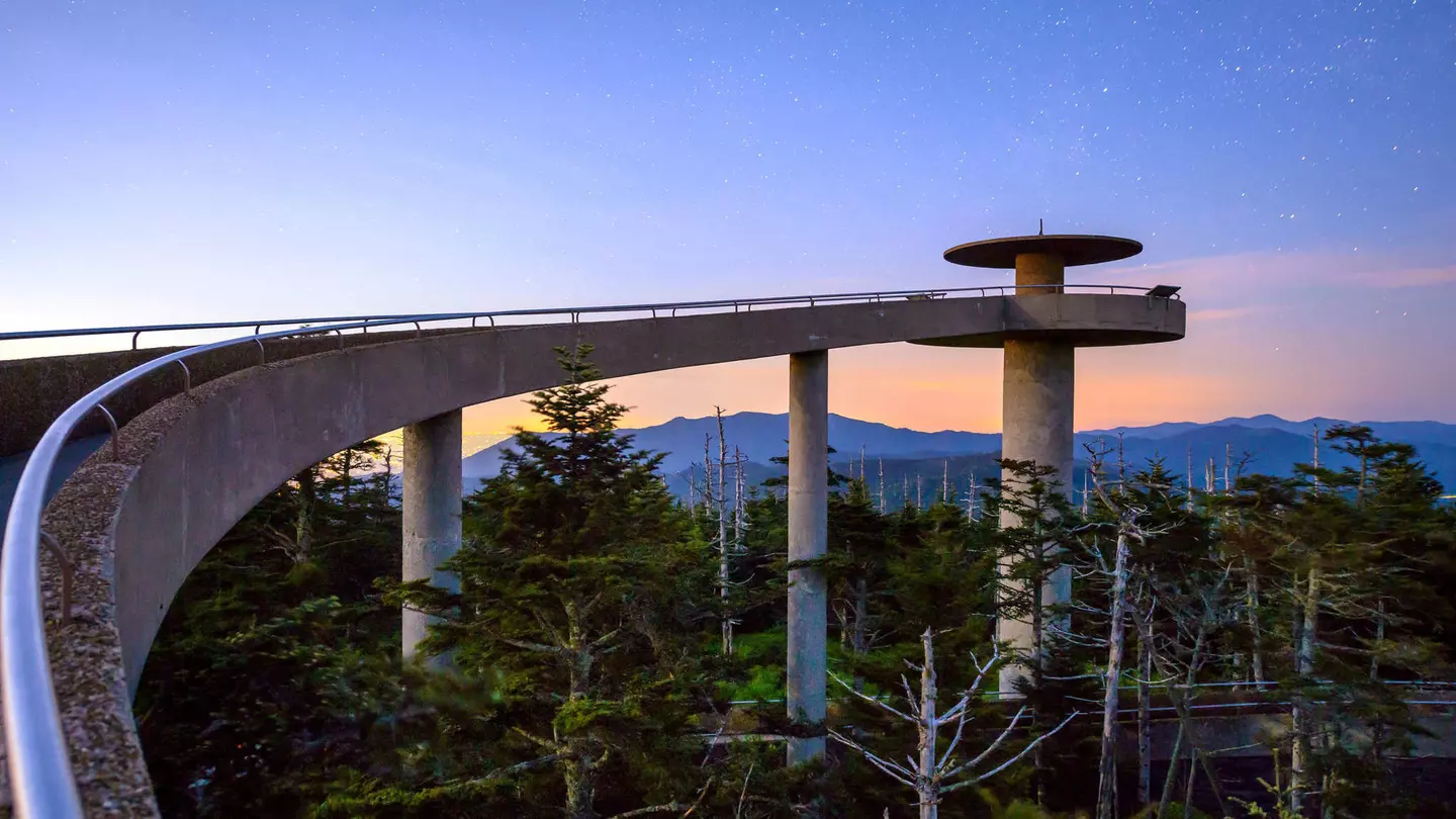 A curving, elevated walkway leading to a circular mountaintop observatory at sunset in the Great Smoky Mountains