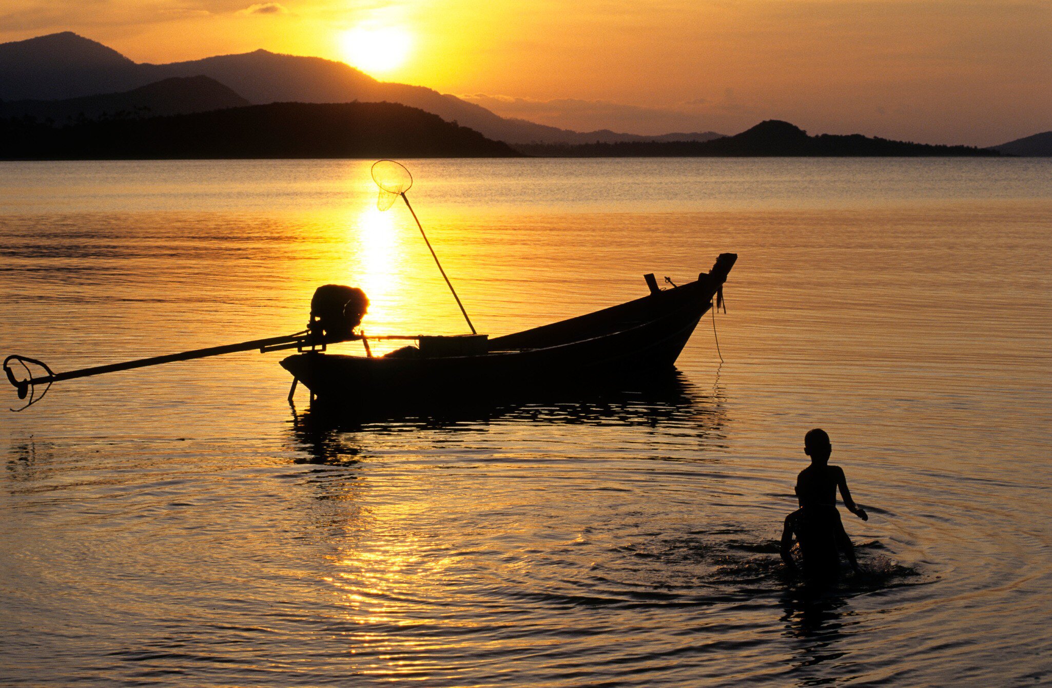 Koh Samui Island, Phang Ka Bay at sunset.  Silhouette of children playing and boat.