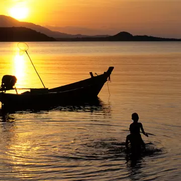 Koh Samui Island, Phang Ka Bay at sunset.  Silhouette of children playing and boat.