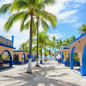 Melaque, Mexico. March 2015. Traditional Mexican single unit bungalows with palm trees and stone embedded  road.