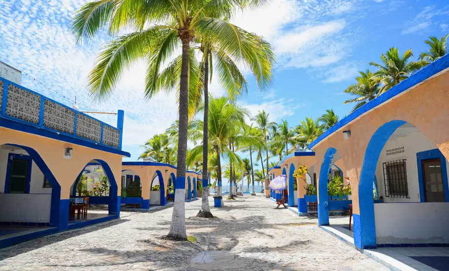 Melaque, Mexico. March 2015. Traditional Mexican single unit bungalows with palm trees and stone embedded  road.