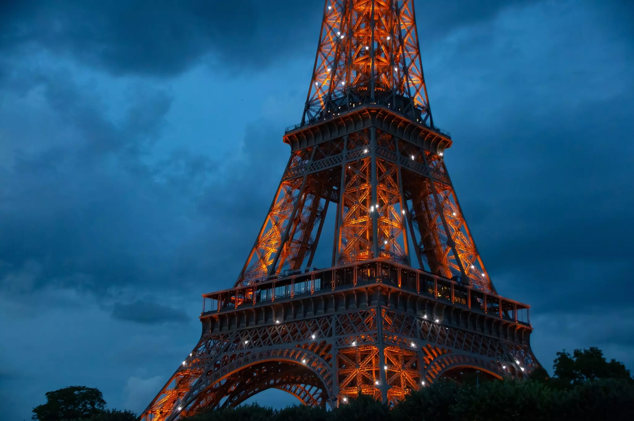 A close up of the Eiffel Tower glowing at dusk in the city of Paris during the summer