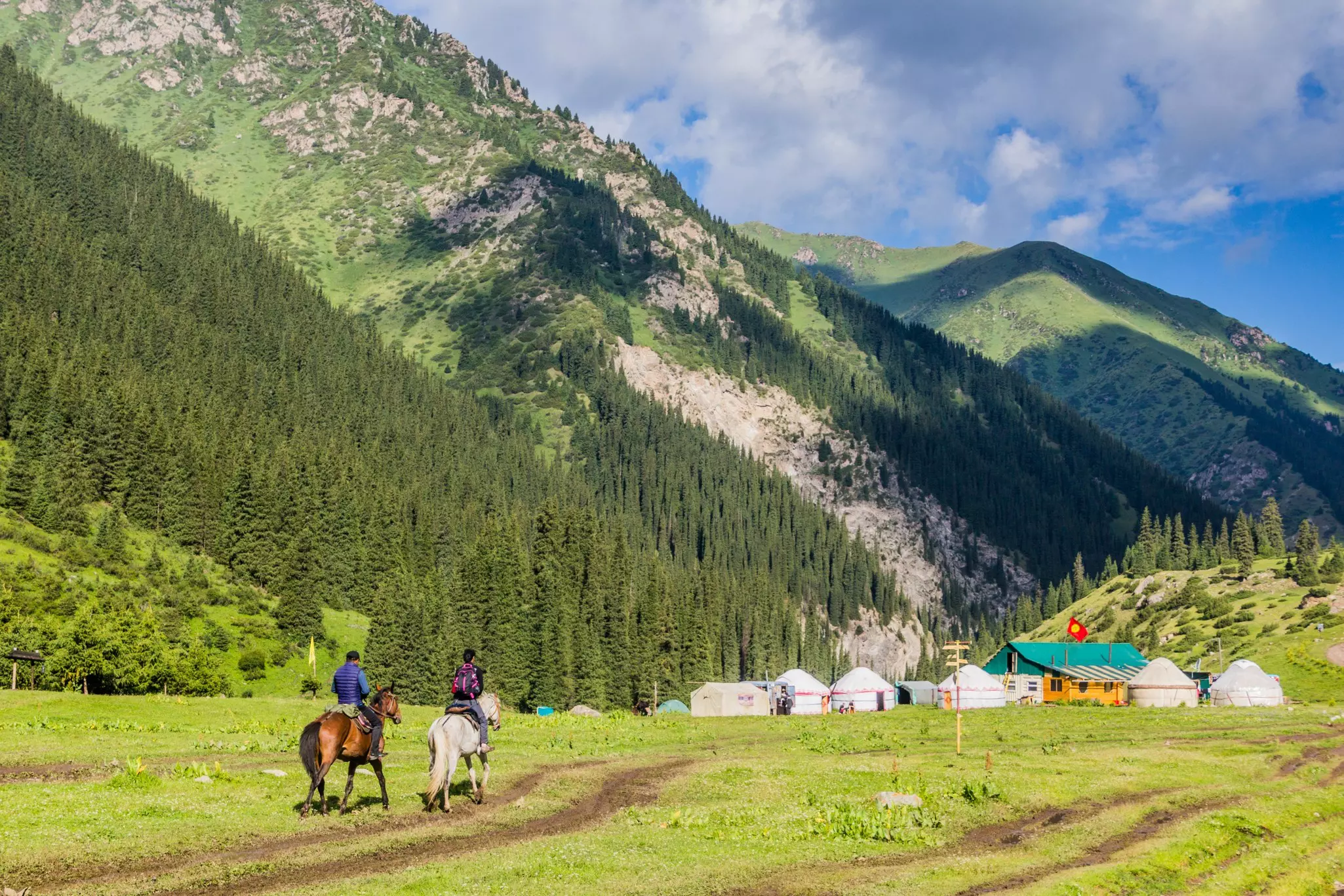 Villagers on horseback near a yurt camp in Altyn Arashan, Kyrgyzstan.