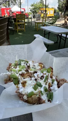 Sour cream and chives on top of a pile of tater tots. 