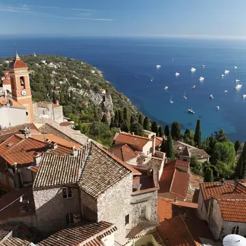 Terracotta tiled roofs of houses in hillside village with Château de Roquebrune. Nice, France.
