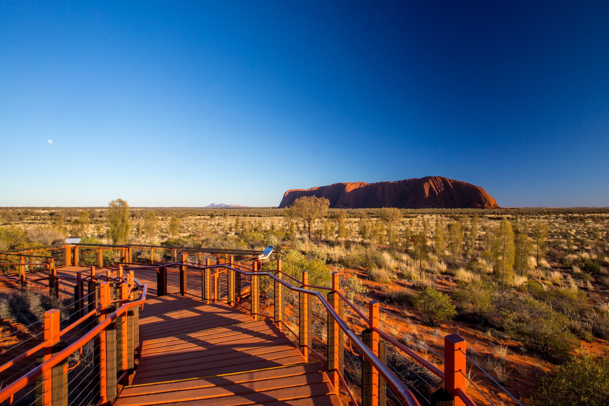 Uluru and the viewing platform at sunrise on a clear winter's morning in the Northern Territory, Australia.