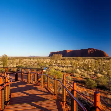 Uluru and the viewing platform at sunrise on a clear winter's morning in the Northern Territory, Australia.