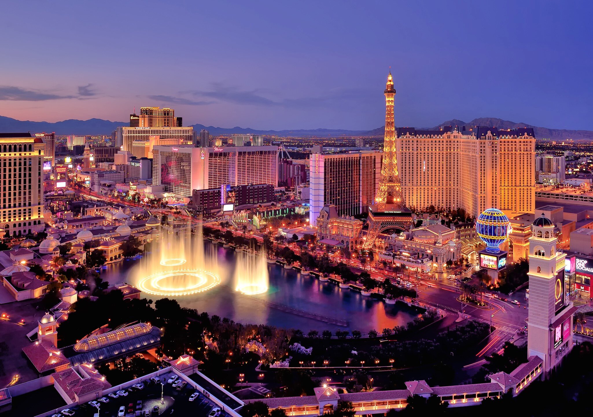 The Las Vegas strip with the fountains of the Bellagio leaping into the air photographed at dusk.
