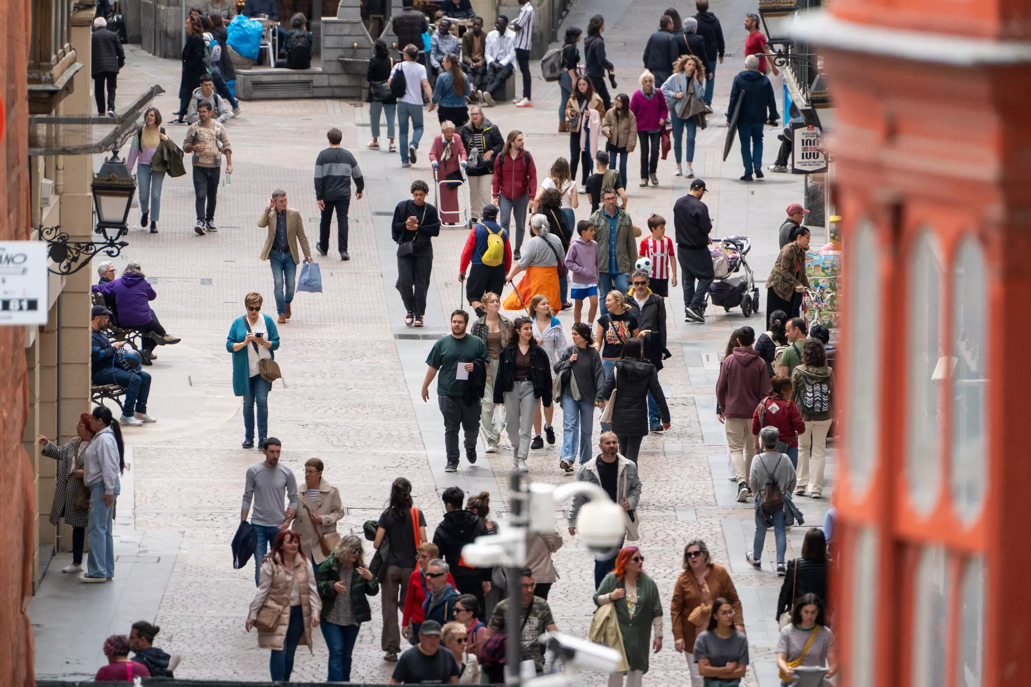A view of people walking down a crowded pedestrianized street in a city.